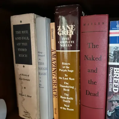 Sale Photo Thumbnail #646: Collection of hardbound vintage books on a wooden shelf, including titles by William L. Shirer, Zane Grey, and Norman Mailer.