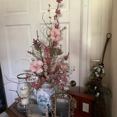 Sale Photo Thumbnail #654: Tabletop display featuring a tall faux floral arrangement in an Asian-style porcelain vase, flanked by an ornate brass picture frame, a glass hurricane candle holder, and holiday decor.