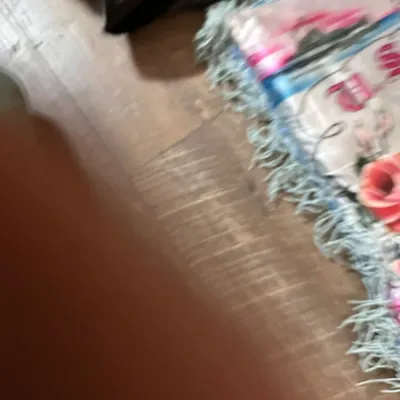Sale Photo Thumbnail #361: Fringed textile or banner featuring a floral pink rose design, shown partially folded on a wooden floor.