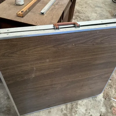 Sale Photo Thumbnail #526: Portable folding table with faux woodgrain laminate top, aluminum trim, and integrated carrying handle.