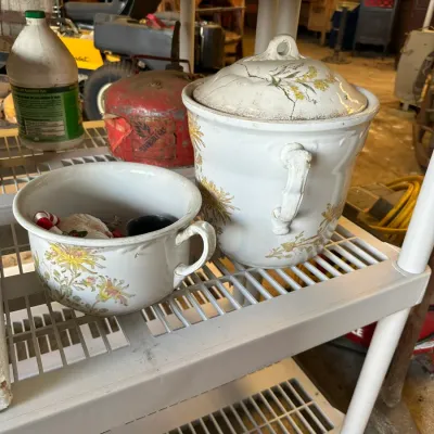 Sale Photo Thumbnail #570: Vintage ceramic chamber pot and covered vessel featuring yellow and pink floral transfers, displayed on a plastic shelving unit.