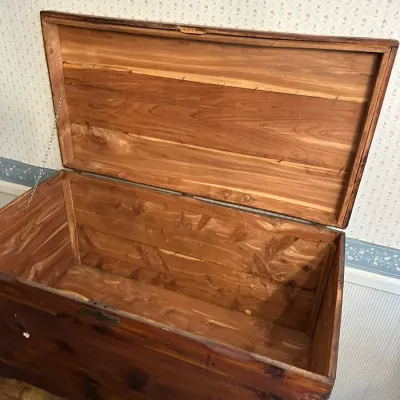 Sale Photo Thumbnail #351: Vintage solid cedar storage chest featuring a hinged lid with a support chain and rich natural wood grain interior.