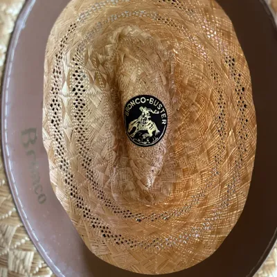 Sale Photo Thumbnail #631: Interior view of a vintage Bronco-Buster woven straw cowboy hat, featuring a brown leather sweatband and branded crown emblem, size 7 1/8.