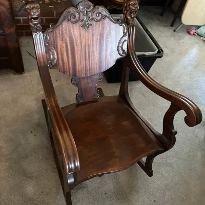 Sale Photo Thumbnail #581: Antique carved mahogany armchair featuring detailed lion head finials and a carved crest rail backrest.