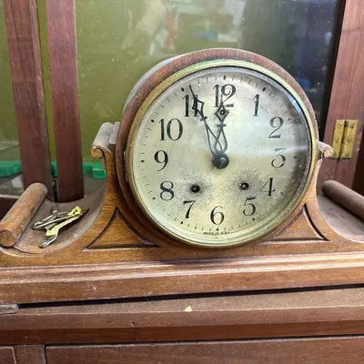 Sale Photo Thumbnail #27: Vintage wooden mantel clock featuring a rounded case with scrolled sides, brass bezel trim, and an aged face marked 'Made in U.S.A.', complete with winding keys.