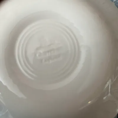 Sale Photo Thumbnail #699: Underside of a white ceramic dish featuring an embossed concentric ring design and maker's mark.