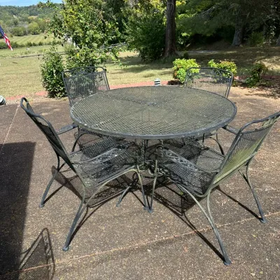 Sale Photo Thumbnail #167: Black wrought iron outdoor patio dining set, including a round mesh-top table and four matching armchairs with scroll detail.