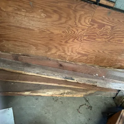 Sale Photo Thumbnail #343: Stack of assorted rough-cut wooden boards and plywood sheets stored against a wall.
