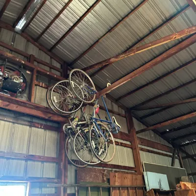 Sale Photo Thumbnail #555: Collection of vintage road bicycles suspended from rafters inside a pole barn storage space.