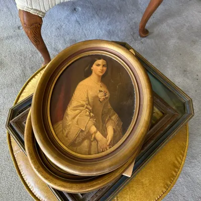 Sale Photo Thumbnail #258: Vintage framed portrait print of a Victorian woman in an oval gilt frame, stacked on top of other framed artwork.