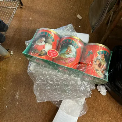 Sale Photo Thumbnail #318: Set of three vintage Coca-Cola holiday popcorn tins in original shrink wrap packaging, featuring classic Santa Claus illustrations.