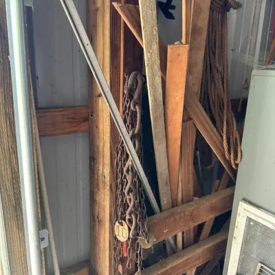 Sale Photo Thumbnail #714: Assorted workshop items including rusty chains with numbered tags, thick rope, and scrap lumber stored in a shed.