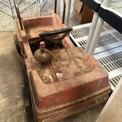 Sale Photo Thumbnail #542: Vintage molded plastic ride-on pedal car with front-mounted bell, showing heavy dirt and age-related wear.