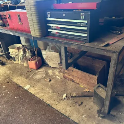 Sale Photo Thumbnail #492: Heavy-duty steel workbench holding a black Craftsman metal tool chest, a red tool box, and various workshop equipment.