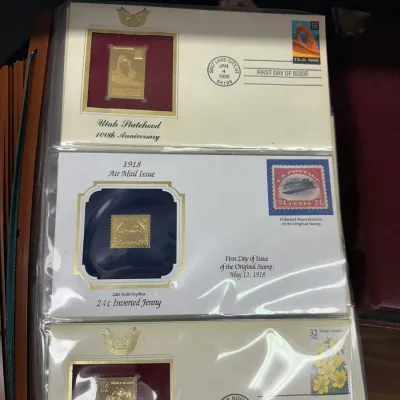 Sale Photo Thumbnail #100: Collection of First Day Covers featuring 22kt gold replica stamps, including the Utah Statehood 100th Anniversary and 1918 Inverted Jenny issues, preserved in plastic sleeves.