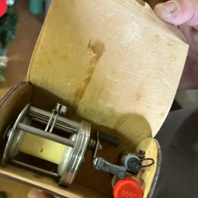 Sale Photo Thumbnail #225: Vintage Ambassadeur 5000 fishing reel housed in its original leather case, complete with extra parts and accessories.