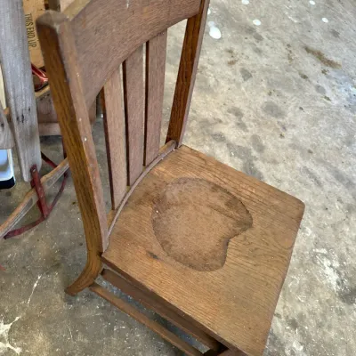 Sale Photo Thumbnail #530: Antique oak dining chair featuring a slat back design with visible finish wear and discoloration on the wooden seat.