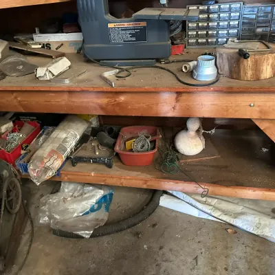 Sale Photo Thumbnail #502: Wooden workbench holding various power tools, hardware, storage drawers, and workshop accessories.
