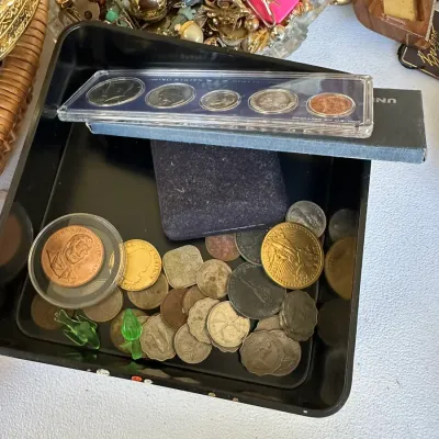 Sale Photo Thumbnail #383: Collection of coins and commemorative medallions resting in a black plastic tray, featuring a encased United States proof set and a John Wayne medallion.