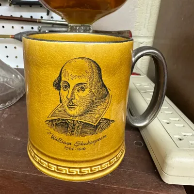 Sale Photo Thumbnail #41: Vintage mustard-yellow ceramic mug featuring a printed portrait of William Shakespeare with fine crazing and a dark silver-toned handle.