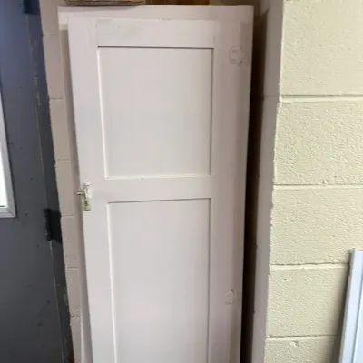 Sale Photo Thumbnail #321: Tall white painted wooden storage cabinet with paneled single door and metal latch, showing general wear.