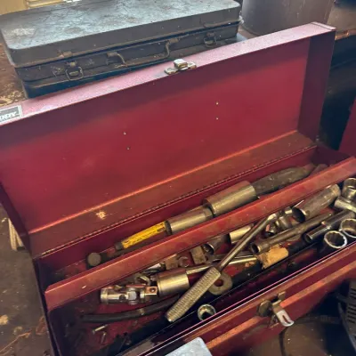 Sale Photo Thumbnail #743: Open red metal toolbox filled with various hand tools, sockets, and ratchets alongside additional vintage toolboxes.