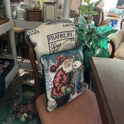 Sale Photo Thumbnail #661: Tapestry Santa and snowman decorative throw pillow displayed on a wooden dining chair with a throw blanket.