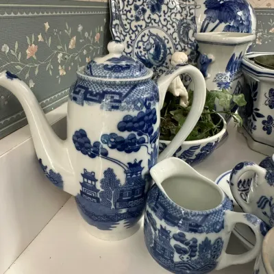 Sale Photo Thumbnail #706: Collection of blue and white Blue Willow porcelain, including a coffee pot, creamer, and decorative platters in excellent condition.