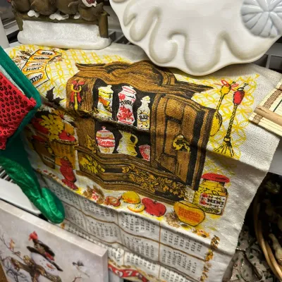 Sale Photo Thumbnail #68: Vintage 1970s kitchen tea towel calendar featuring a spice hutch illustration, alongside ceramic Christmas decor items.