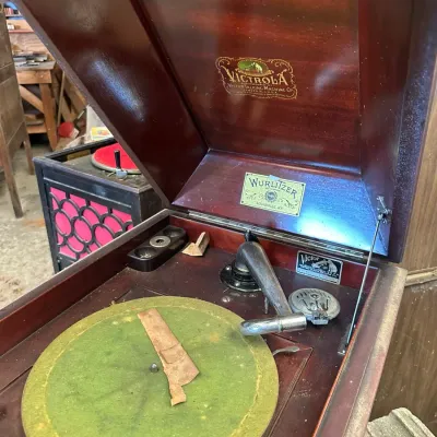 Sale Photo Thumbnail #525: Antique Victrola Talking Machine phonograph in a mahogany cabinet, featuring a green felt turntable and Wurlitzer dealer plate.
