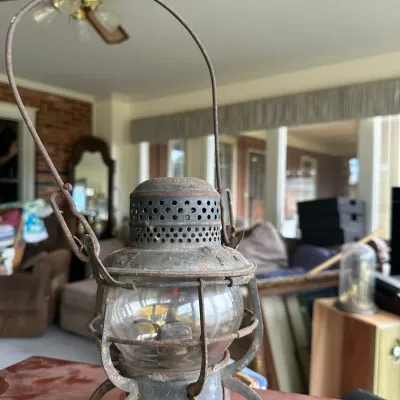 Sale Photo Thumbnail #228: Vintage Armspear railroad lantern featuring a weathered metal frame, tall wire bail handle, and clear glass globe.