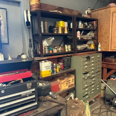 Sale Photo Thumbnail #745: Workshop area featuring a green multi-drawer metal card catalog cabinet, a Craftsman portable metal toolbox, and shelving filled with various hardware and chemical supplies.