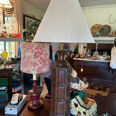 Sale Photo Thumbnail #192: Pair of vintage table lamps, including a tall carved dark wood lamp with a pleated white shade and a smaller red candle-style lamp with a toile shade.