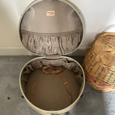 Sale Photo Thumbnail #363: Vintage off-white Samsonite round hat box suitcase shown open, featuring a taupe satin-lined interior with elasticized pockets and tie-down straps.