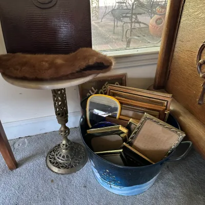 Sale Photo Thumbnail #253: Vintage dark brown faux-alligator handbag displayed with a fur collar on a brass pedestal table alongside a tub filled with assorted picture frames.