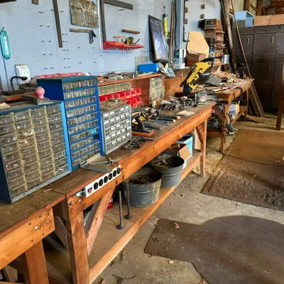 Sale Photo Thumbnail #503: Workshop area featuring heavy-duty wooden workbenches, wall-mounted tool storage, plastic hardware drawers, power tools, and various hardware accessories.