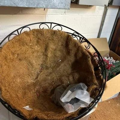 Sale Photo Thumbnail #52: Large black metal hanging planter basket with a fibrous coco coir liner, showing light soil residue.