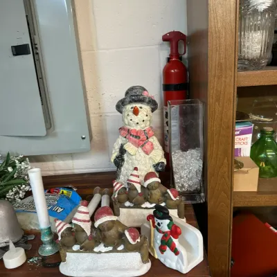 Sale Photo Thumbnail #297: Collection of holiday table decor including a textured snowman figurine, bird sets in winter hats on snowy benches, and a small snowman napkin holder.