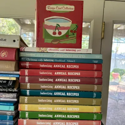 Sale Photo Thumbnail #259: Stack of Southern Living Annual Recipes and Christmas cookbooks spanning the 1980s and 1990s, topped with a cherry-themed Recipe Card Collection binder.