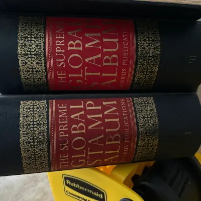 Sale Photo Thumbnail #152: Two volumes of The Supreme Global Stamp Album by Minkus Publications, featuring black leatherette spines with gilded and red detailing.