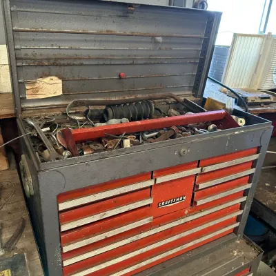 Sale Photo Thumbnail #482: Vintage Craftsman metal tool chest filled with various hand tools, hardware, and automotive parts, showing age-appropriate wear and patina.