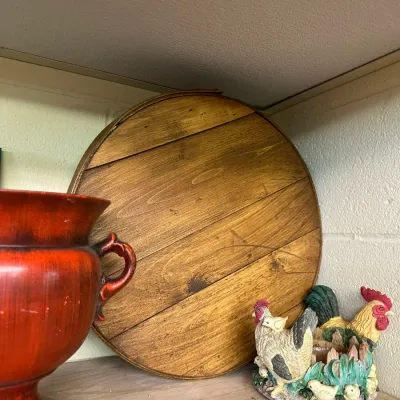 Sale Photo Thumbnail #66: Round wooden cheese crate lid displayed on a shelf next to a reddish-orange ceramic vase and a rooster figurine.
