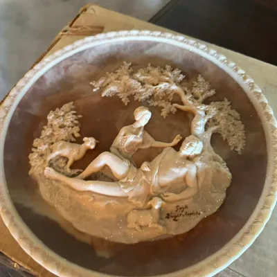 Sale Photo Thumbnail #190: Incolay stone collector plate featuring a detailed relief sculpture of a classical romantic scene with figures and sheep under a tree.