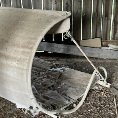 Sale Photo Thumbnail #328: Vintage porch glider or outdoor swing canopy with metal frame and worn fabric, showing significant tears and weathering.