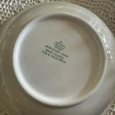 Sale Photo Thumbnail #587: Underside of a vintage white ceramic ironstone plate, showing a green crown backstamp that reads 'Ironstone China Hand Painted Oven & Craze Proof'.