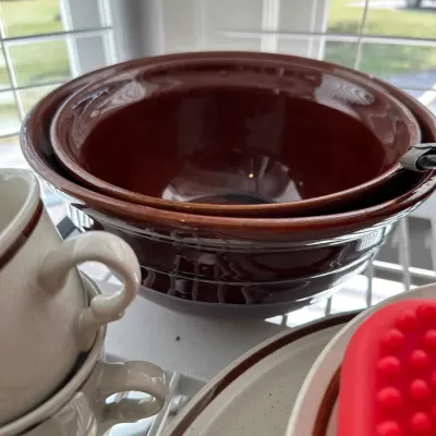 Sale Photo Thumbnail #694: Set of nested brown glazed ceramic mixing bowls alongside speckled stoneware mugs and plates.