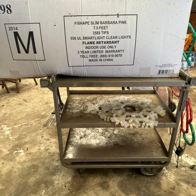 Sale Photo Thumbnail #546: Boxed 7.5-foot F/Shape Slim Barbara Pine artificial Christmas tree with 550 clear lights, resting on a three-tier metal utility cart.
