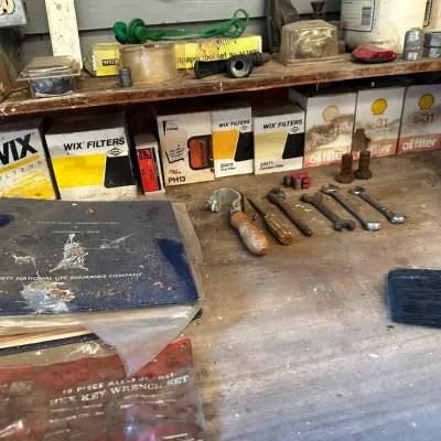 Sale Photo Thumbnail #477: Workshop workbench featuring assorted vintage hand tools, wrenches, a paint brush, a Liberty National Life Insurance binder, and vintage boxed Wix and Shell oil filters.