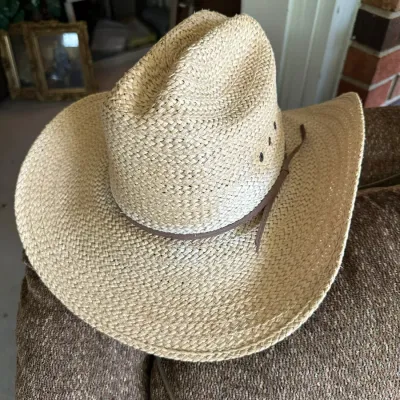 Sale Photo Thumbnail #634: Natural woven straw cowboy hat featuring a brown leather hatband with a side tie.