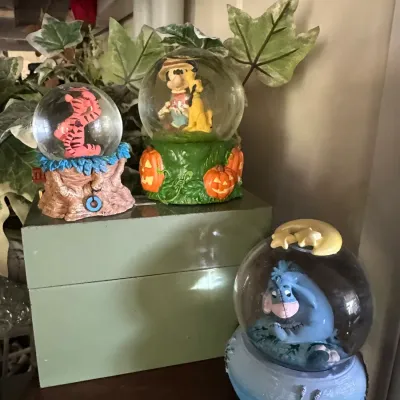 Sale Photo Thumbnail #237: Trio of Disney collectable snow globes featuring Tigger, Mickey Mouse with Pluto, and Eeyore, set on resin decorative bases.